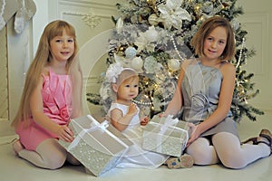 Three girls sisters sitting at the Christmas tree