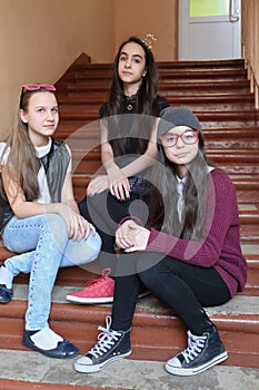 Three girls sitting together on stairs at school,