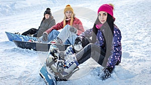 Three girls snowboarders sitting on the snow