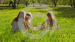 Three girls in striped dresses are making wreath in the apple garden