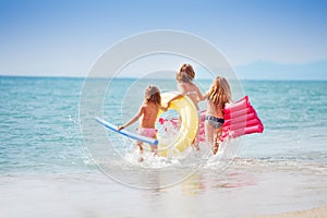 Three girls with swimming tools running to the sea