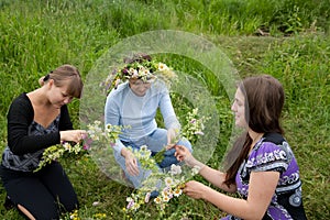 Three girls is twist flowers into a wreath