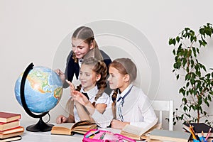 Three girls watching the globe in geography class
