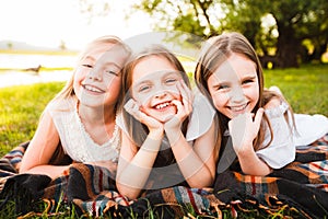 Three girls in white dresses walk in nature in the summer. Children`s pastime during the summer holidays.