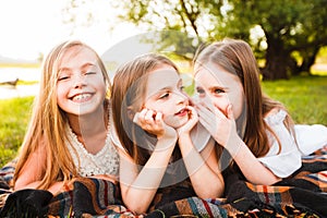 Three girls in white dresses walk in nature in the summer. Children`s pastime during the summer holidays.