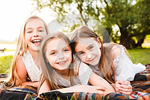 Three girls in white dresses walk in nature in the summer. Children`s pastime during the summer holidays.