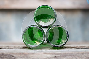 Three glass bottles, green bottoms lie ahead on wooden