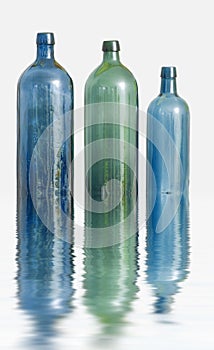 Three glass bottles on white surface with water effect. Old colorful vintage wine bottles arranged against a copy space