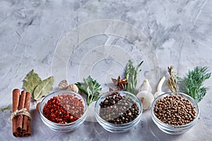 Three glass bowls with spices arranged in rows on white textured background, view from above.