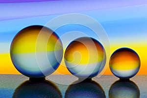 Three glass crystal balls in a row with a rainbow of colorful light painting behind them