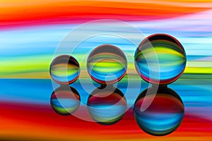 Three glass crystal balls in a row with a rainbow of colorful light painting behind them