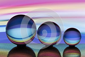 Three glass crystal balls in a row with a rainbow of colorful light painting behind them