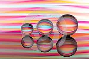 Three glass crystal balls in a row with a rainbow of colorful light painting behind them