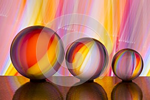 Three glass crystal balls in a row with a rainbow of colorful light painting behind them