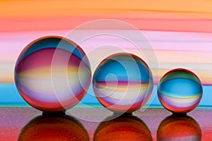 Three glass crystal balls in a row with a rainbow of colorful light painting behind them