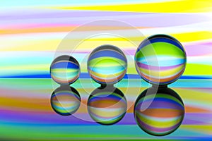 Three glass crystal balls in a row with a rainbow of colorful light painting behind them