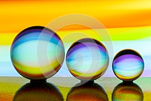 Three glass crystal balls in a row with a rainbow of colorful light painting behind them