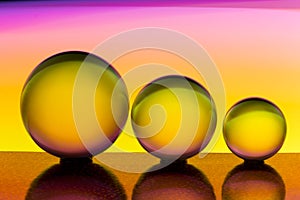 Three glass crystal balls in a row with a rainbow of colorful light painting behind them