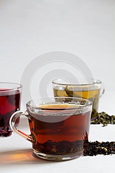 Three glass cups with black, red and green tea on a white background.