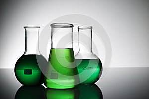 Three glass flask placed in a laboratory table with green liquid