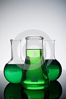 Three glass flask placed in a laboratory table with green liquid