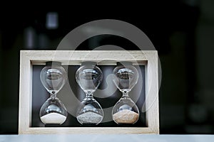 Three glass hourglasses with colored sand