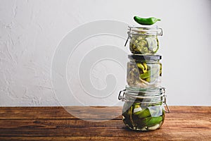 Three Glass Jars of Freshly Canned Jalapeno Peppers with Herbs and Garlic
