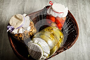 three glass jars with homemade canned vegetables lie in basket