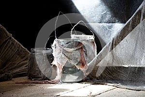 Three glass jars wrapped in white dirty cloth stand on the floor of the house, Halloween decor