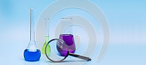 Three glass laboratory flasks with blue, green and purple solutions on a gentle blue medical background. The concept of medical
