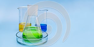 Three glass laboratory flasks with solutions of yellow, green and blue on a gentle blue medical background. The concept of medical