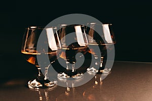 Three glasses of cognac on a dark background