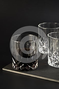 Three glasses for cognac stand on a stand on a dark background