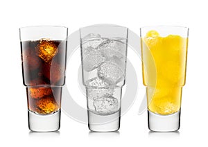 Three glasses with cola soft drink with orange soda and lemonade with ice cubes on white