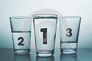 three glasses with different amount of water and rank numbers like medals podium - conceptual style