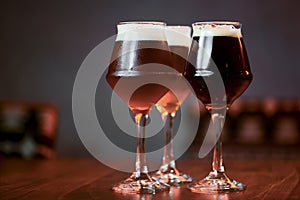 Three glasses with different beer on wooden table in a bar. Food photography concept, with copy space
