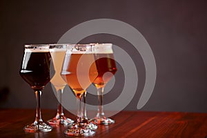 Three glasses with different beer on wooden table in a bar. Food photography concept, with copy space