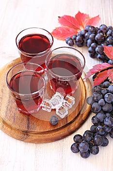 Three glasses of grape juice with ice and black grapes