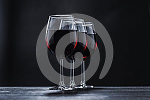 Three glasses of red wine solemnly stand in a row on a table