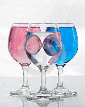 Three glasses of water with pink and blue