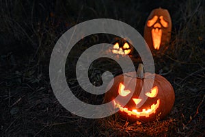 Three Glowing spooky Halloween pumpkin on the ground at night.