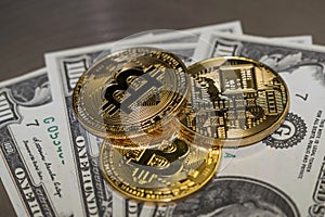 Three gold bitcoin coins and american dollars close-up