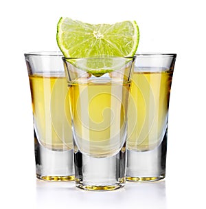 Three gold tequila shots with lime isolated on white photo