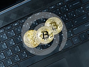 Three golden bitcoins on keypad of laptop black color the digital money cryptocurrency concept