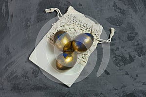 Three golden - blue eggs with decorative pocket on dark shale background