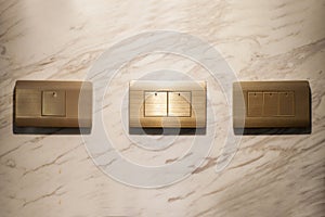 Three golden lighting switchs on wall, on and off