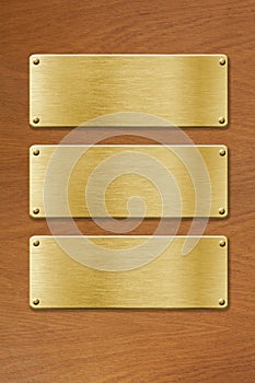 Three golden metal plates over wood texture background