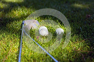 Three golf balls and golf clubs on green