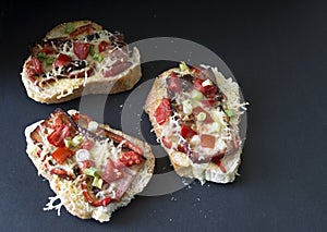 Three gourmet bruschetta made of bacon, tomatoes