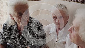 Three grandmothers having pleasant talk on sofa in room